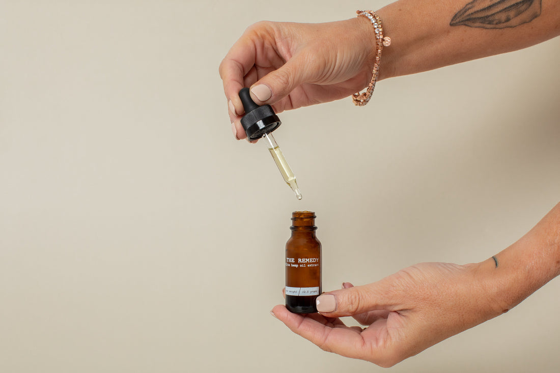 Hand holding dropper above oil bottle