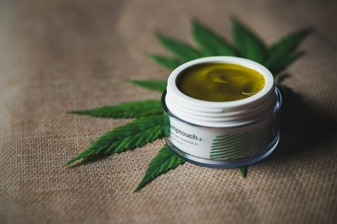 Jar of hemp cream on cannabis leaves