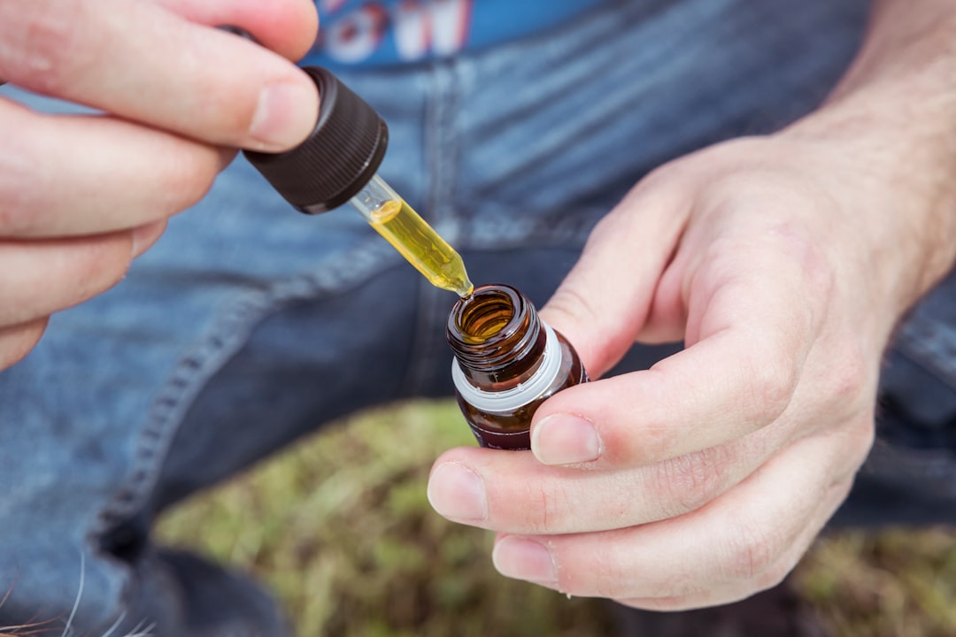 Hand holding CBD oil dropper bottle