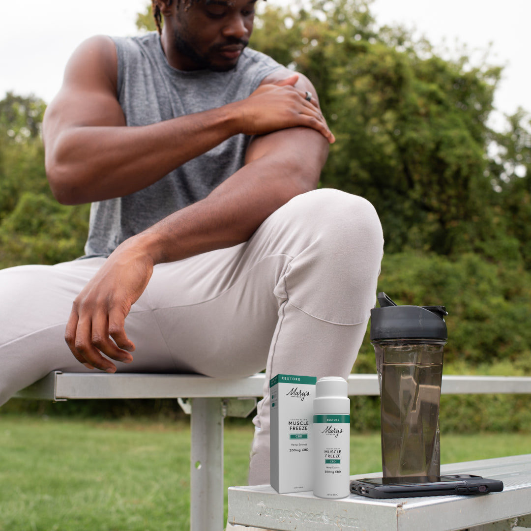 Man sitting outdoors with Muscle Freeze products on a bench
