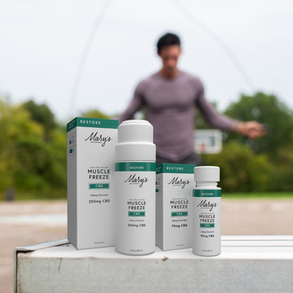Mary's CBD Muscle Freeze products on a surface with a blurred background of a person exercising outdoors.